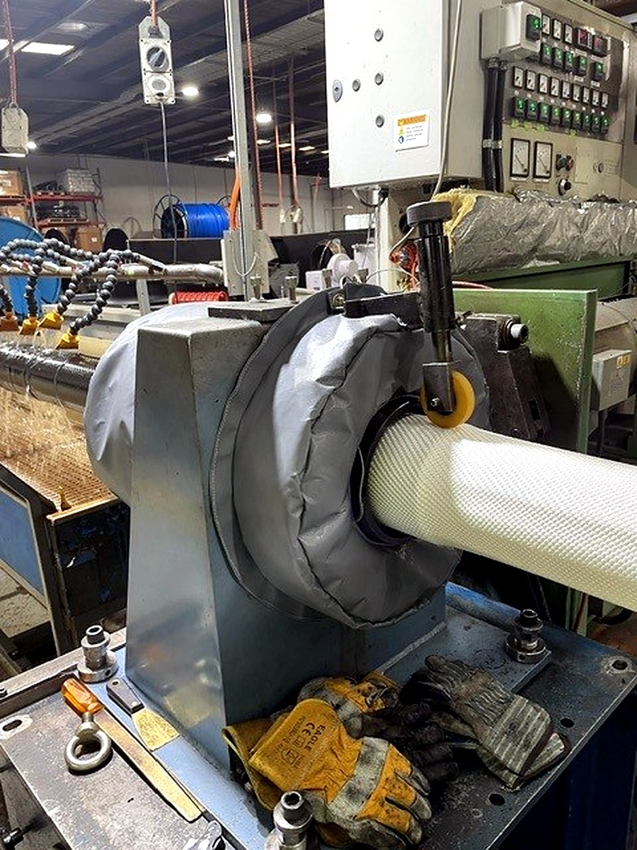 Thermal jacket fitted to an industrial machine bearing housing on a factory floor